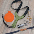 Hornet slingshot flat lay with bandsets, clay and steel ammo, lanyard and tape